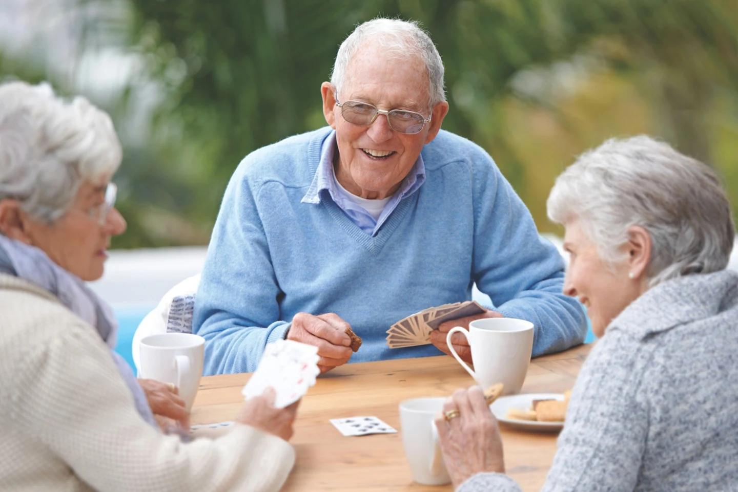 Three older adults enjoying a card game together.
