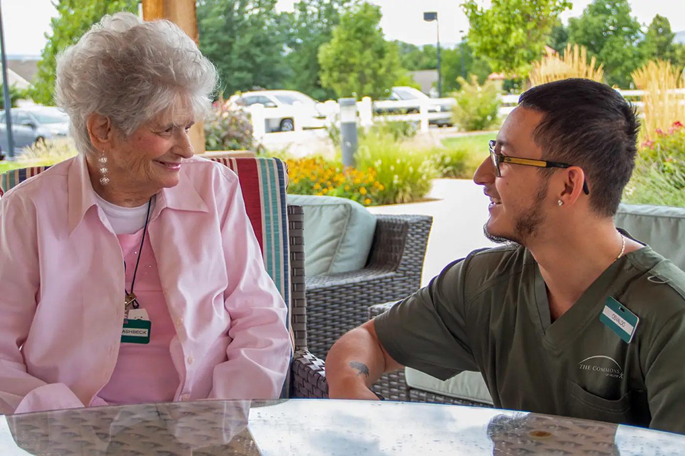 Resident and caregiver connecting in outdoor seating area at The Commons senior living in Grand Junction